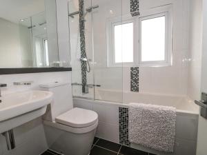 a white bathroom with a toilet and a sink at Sandy Toes in Christchurch +36 photos