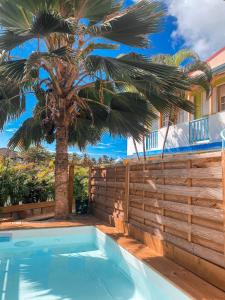 ein Pool mit einer Palme neben einem Zaun in der Unterkunft Hotel Oasis in Grande Anse