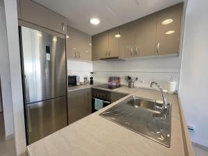 a kitchen with a sink and a stainless steel refrigerator at Samsara Beach in Port d'Alcudia