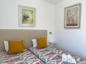 a bedroom with a bed with two pillows and two pictures at Mouraliz Apartments by HD PROPERTIES - Vilamoura Marina in Vilamoura