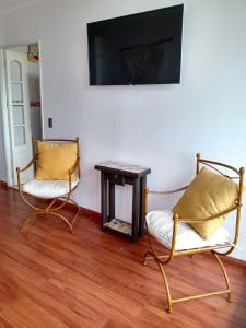 two chairs and a table in a room with a tv at Departamento frente al mar 3 habitaciones 2 baños in Coquimbo