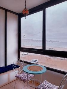 ein Tisch und Stühle in einem Zimmer mit Blick auf den Strand in der Unterkunft Departamento frente al mar 3 habitaciones 2 baños in Coquimbo