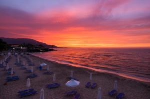 una playa con sillas y sombrillas al atardecer en Kernos Beach Hotel & Bungalows, en Malia