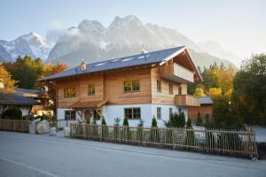a large wooden house with mountains in the background at Zugspitzerei - Premium Chalet Ferienwohnungen in Grainau