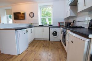 een keuken met witte kasten en een wasmachine en droger bij Sophias House- Short walk to Town and Seafront in Torquay