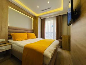 ein Schlafzimmer mit einem Bett mit gelben Kissen und einem TV in der Unterkunft Zem Hotel in Istanbul