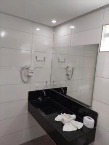 a bathroom with a sink and a mirror and towels at Pousada Sunset Boipeba in Ilha de Boipeba