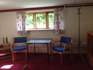 een kamer met 2 stoelen, een tafel en een raam bij Murermester Madsens Villa in Otterup
