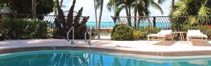 una piscina con due sedie e un tavolo e l'oceano di Kona Kai Resort and Gallery a Key Largo