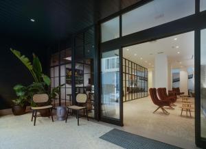 a lobby with chairs and tables and glass doors at Dormirdcine Alicante in Alicante