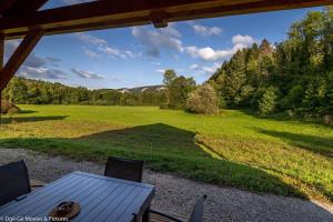 a table and chairs on a porch with a view of a field at Les Jardins du Hérisson Chalet 1 in Bonlieu