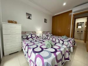 a bedroom with two beds with purple and white sheets at Samsara Beach in Port d'Alcudia