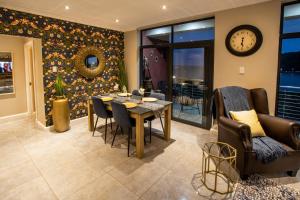 a dining room with a table and chairs and a clock at Stay at The Point- Royal Relaxing Retreat in Durban