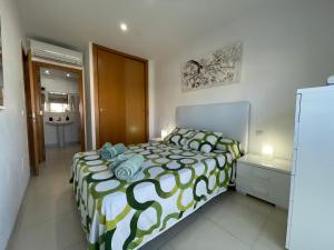 a bedroom with a bed with a green and white comforter at Samsara Beach in Port d'Alcudia