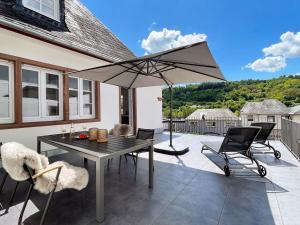 a patio with a table and chairs and an umbrella at Villa Burglay in Zell an der Mosel