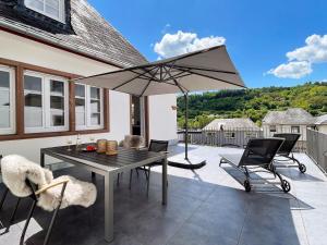 Un patio con una mesa y sillas y una sombrilla. en Villa Burglay, en Zell an der Mosel