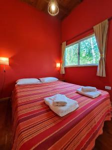 a red bedroom with two beds with towels on them at Cabaña Sol de Medianoche Delta Tigre in Tigre