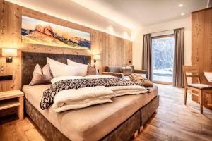 a bedroom with a large bed and a large window at Luxury Chalet Plazola in Selva di Val Gardena