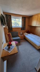 ザンクト・アントン・アム・アールベルクにあるHotel Garni Friedheimのベッド1台とソファが備わる小さな客室です。