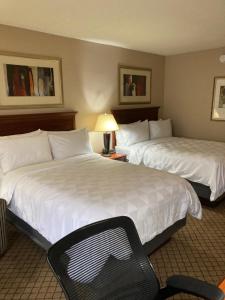 a hotel room with two beds and a chair at Holiday Inn Cincinnati-Eastgate, an IHG Hotel in Eastgate