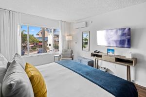 Sea Harbor Hotel - San Diego في سان دييغو: غرفة نوم بسرير ومكتب ونافذة