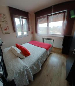 1 dormitorio con 1 cama con almohadas rojas y 2 ventanas en Hotel Sebreñu, en Sebreño