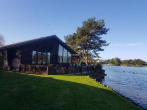 a cabin on a lake with ducks in the water at Keer lodge - Pine Lake Resort in Carnforth
