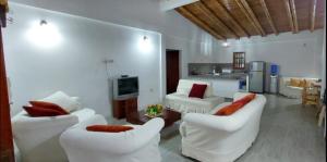 a living room with two white couches and a kitchen at LA CASA MANGLAR Cabañas in Santa Elena