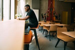 a man sitting on a table in a room with tables and chairs at CAB20 in Hamburg