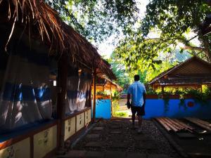 a man walking down a walkway towards a building at Mapping Hostel in Chiang Mai