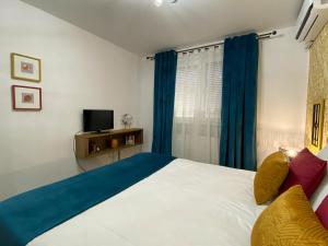 a bedroom with a bed with blue curtains and a television at Autumn Bliss Apartment in Timişoara
