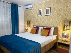 a bedroom with a large bed with blue and red pillows at Autumn Bliss Apartment in Timişoara