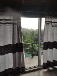 a window with curtains and a view of a balcony at Kandy Penhouse in Kandy