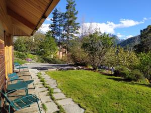 a porch with chairs and a lawn with mountains in the background at Le Carré de Bois in Briançon
