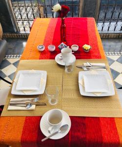 una mesa con platos, tazas y utensilios. en Riad Green Palm, en Marrakech