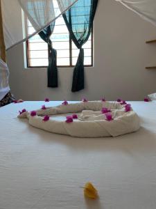 a bed with a pillow with pink flowers on it at Kasuku Villa in Jambiani