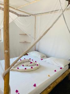 a bed in a tent with flowers on it at Kasuku Villa in Jambiani