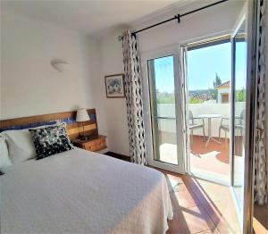 a bedroom with a bed and a balcony with a table at Casa Morgado in Tavira