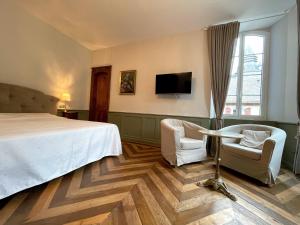 a hotel room with a bed and two chairs and a tv at Maison d'hôtes Le Couvent in Bagnères-de-Bigorre