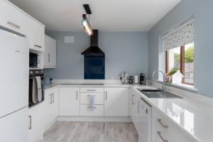 a white kitchen with white cabinets and a sink at Wonderful Coastal home in Dingle town in Dingle