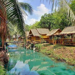 un río en un pueblo con cabañas de bambú en Nakhon Si Ban Na Homestay, en Nakhon Si Thammarat