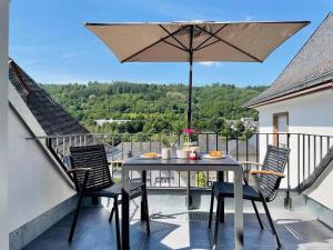 una mesa y sillas en un balcón con sombrilla en Villa Burglay, en Zell an der Mosel