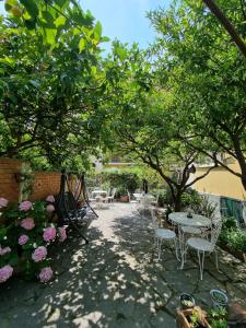 un patio con mesas, sillas, árboles y flores en Villa Pina, en Laigueglia