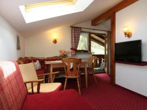 ein Wohnzimmer mit Tisch und Stühlen und einem Fernseher in der Unterkunft Haus am Reschenberg Ferienwohnungen in Ramsau bei Berchtesgaden