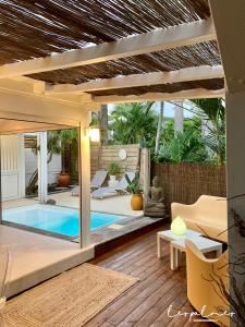 une terrasse avec une piscine dans une maison dans l'établissement 17 Les Palmes - Maison de charme - Piscine privée et accès plage, à Sainte-Anne