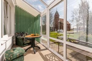 un salón acristalado con mesa, silla y ventanas en Vieno miegamojo apartamentai Juodkrantėje, en Juodkrantė