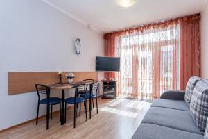Una sala de estar con una mesa y sillas y un sofá. en Vieno miegamojo apartamentai Juodkrantėje, en Juodkrantė