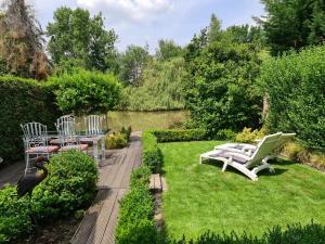 - un jardin avec des chaises blanches, une table et un oiseau dans l'établissement Rent & Relax: De steiger, à Geel