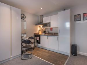 a kitchen with white cabinets and a table and chairs at Pass The Keys Cosy High Street Studio with Free Parking in Lincoln