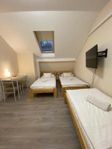 Zimmer mit 2 Betten, einem TV und einem Tisch in der Unterkunft Kiskakas Étterem in Zalaegerszeg